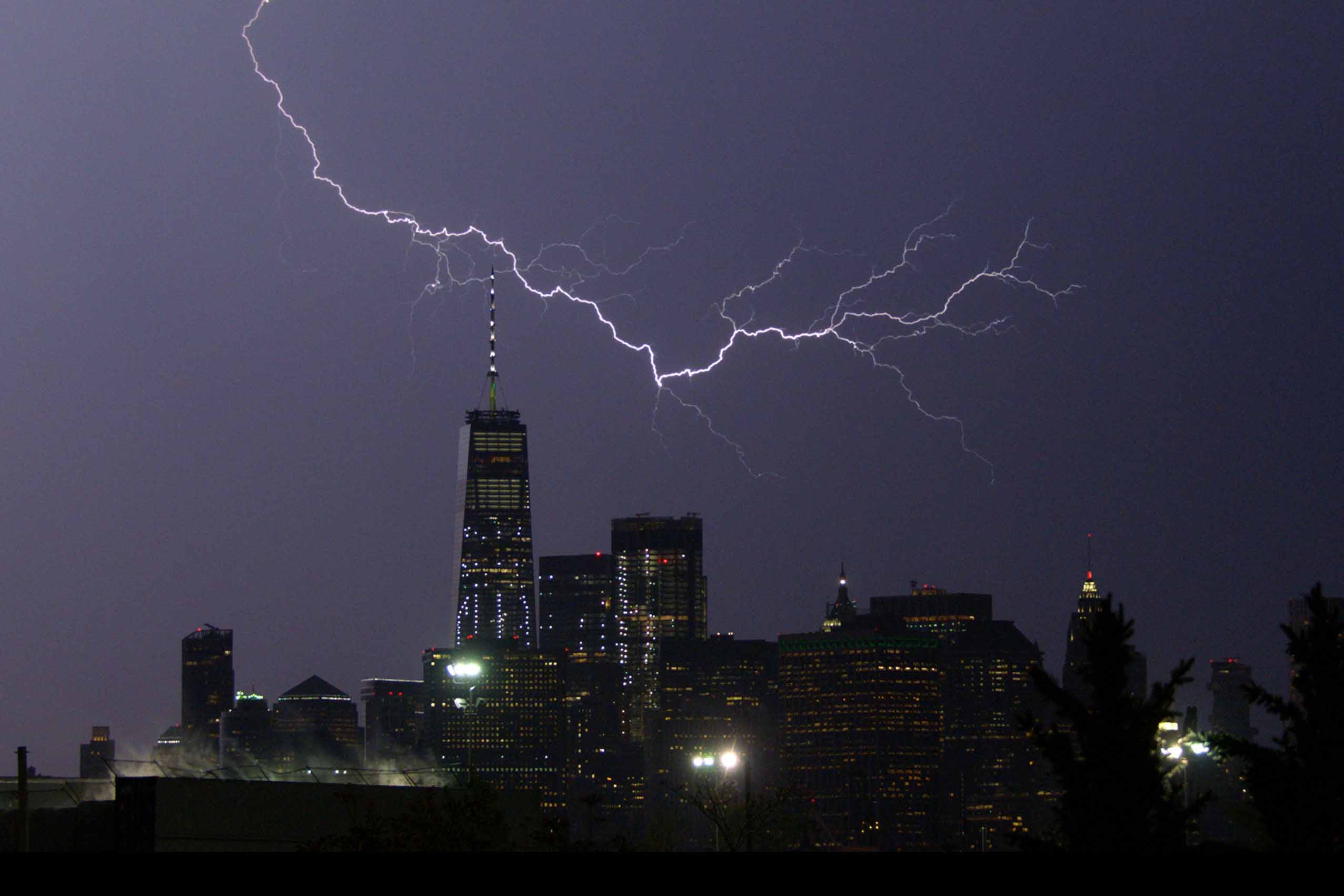 Lightning striking over city skyline at night.