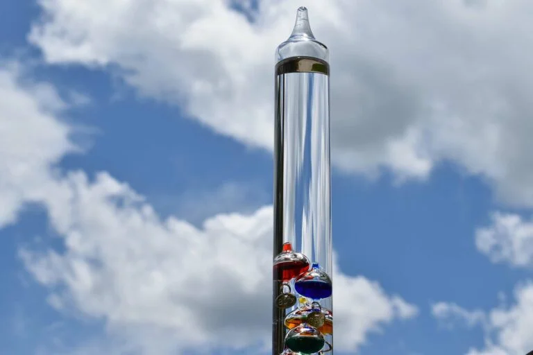 Galileo-thermometer met blauwe lucht en wolken op de achtergrond.