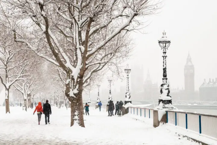 People walking in snowy London near Big Ben.