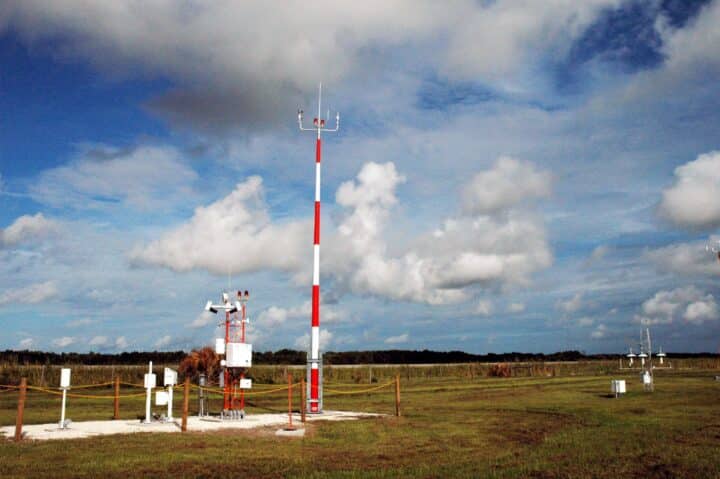 Estação meteorológica com sensores e antenas em campo.